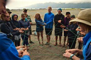 A group of people connected by a continuous strand of string they are holding at various angles